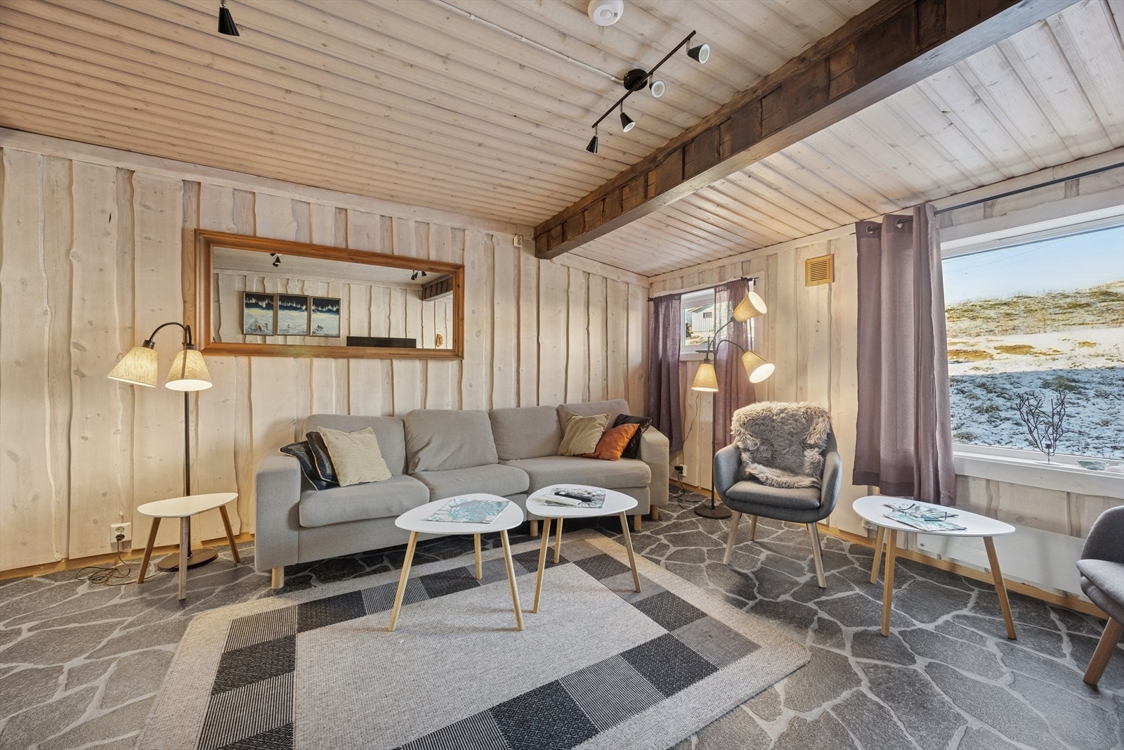 Stuen er innbydende med belegg på gulvet og vegger kledd med villmarkspanel Galleribilde