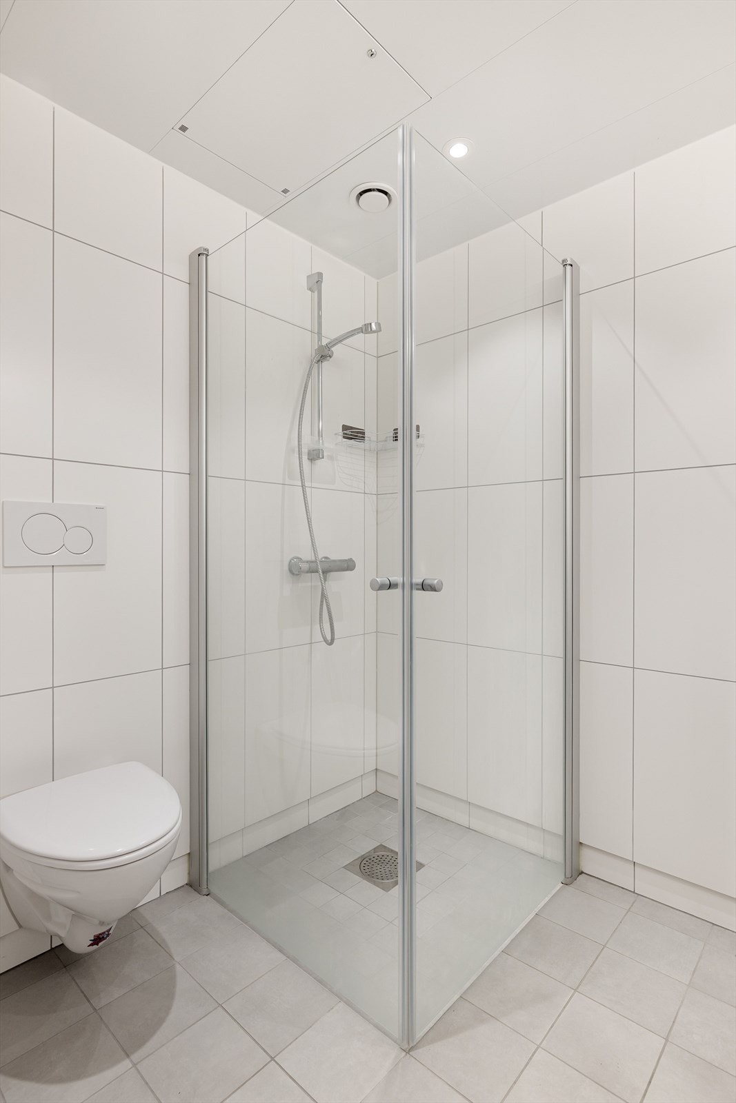 I tillegg har badet et veggmontert toalett og dusjhjørne med innfellbare dusjdører og vegghengt dusjbatteri. Galleribilde