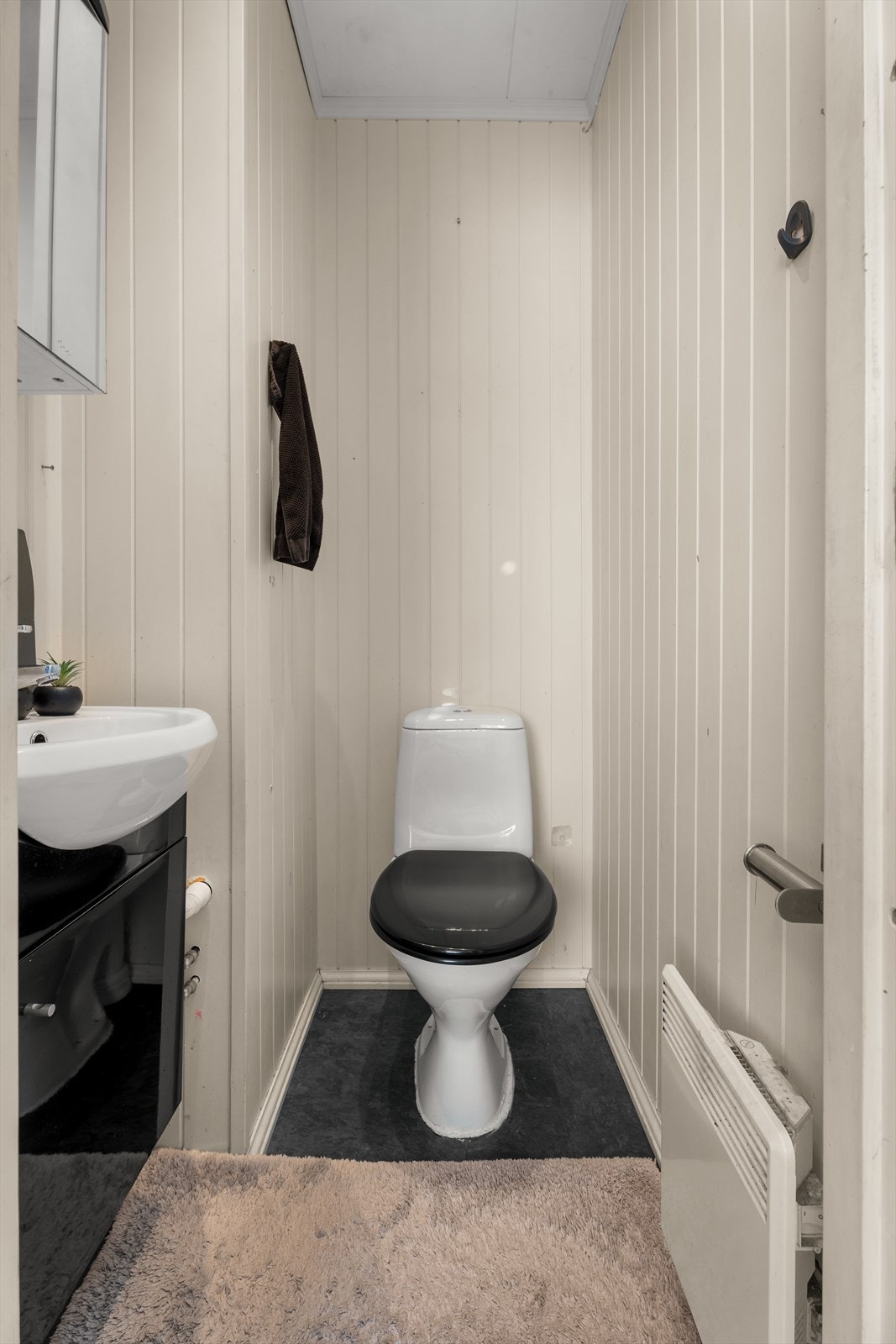 Boligen har et toalett som er utstyrt med gulvtoalett, servant med skap og speilskap. Veggene består av smartpanel, gulvet av laminat og takess i himling. Galleribilde