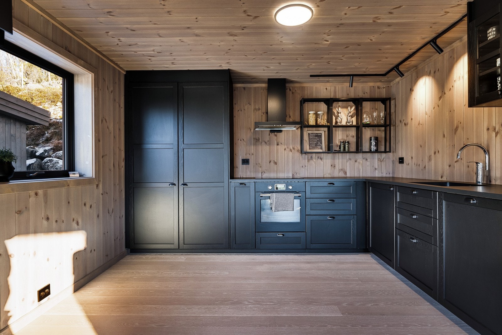 Moderne kjøkkeninnredning fra Ikea med integrerte hvitevarer og råtøff vegghengt hylle som medfølger i salget. Galleribilde