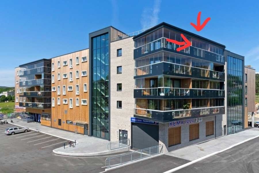 Bygget utvendig. Bygget har nylig blitt malt, og har en mørkere fasade enn på bildet. Piler viser leiligjeten. Galleribilde