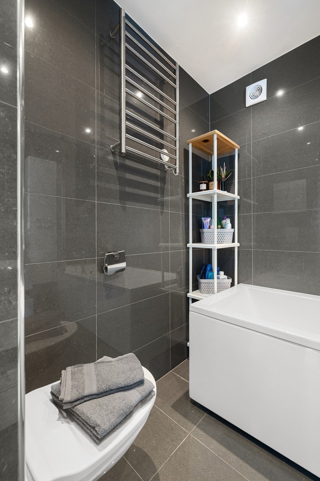 Badet inneholder vegghengt toalett, servant i baderomsinnredning og badekar med dusj. Galleribilde