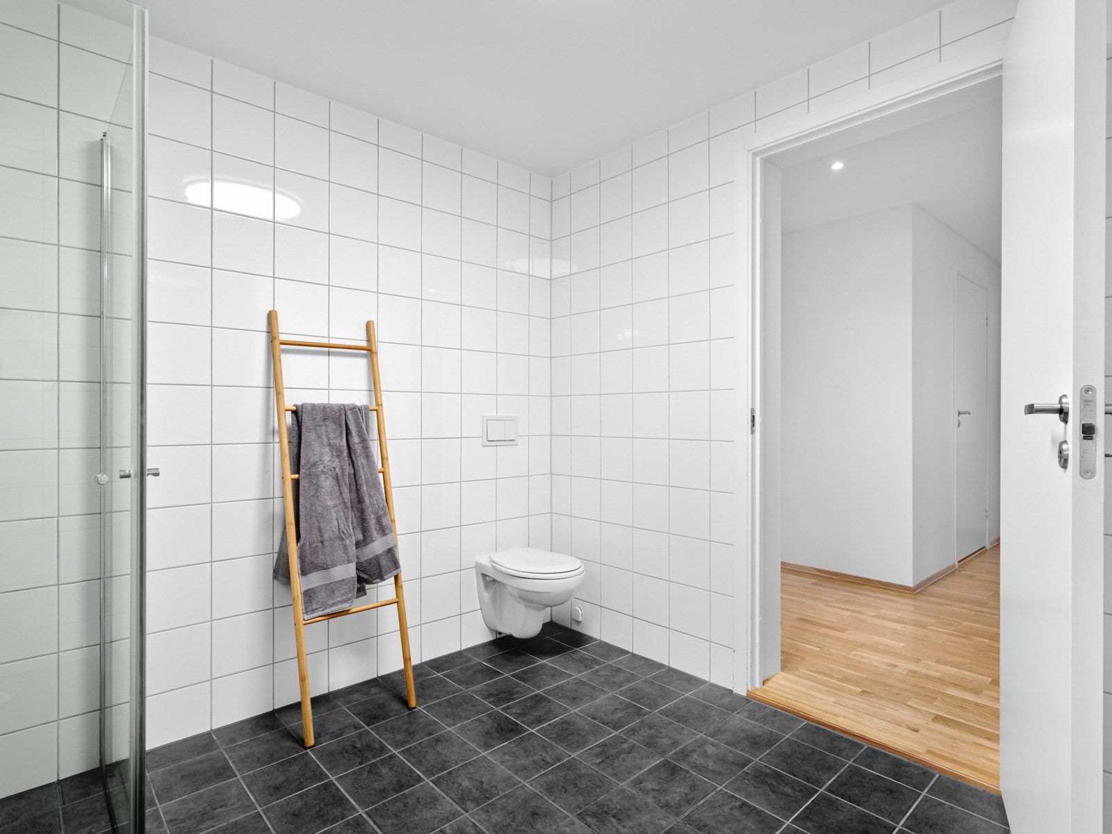 Leiligheten har i dag et romslig bad/vaskerom. Det er fliser på gulv og vegger. Galleribilde