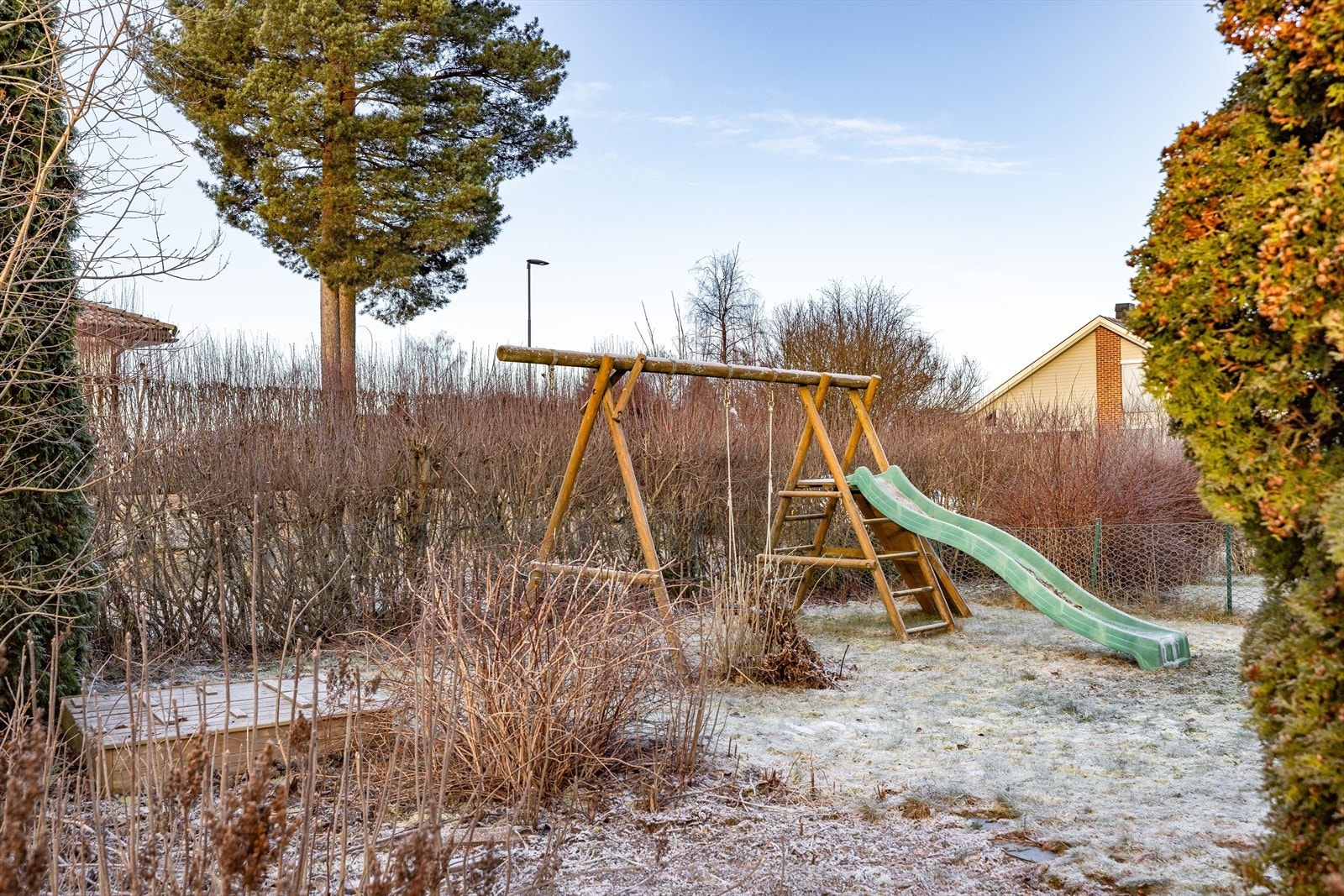 Utenfor terrassen er det en koselig hage opparbeidet med plen, beplantning, sandkasse og lekestativ. Galleribilde