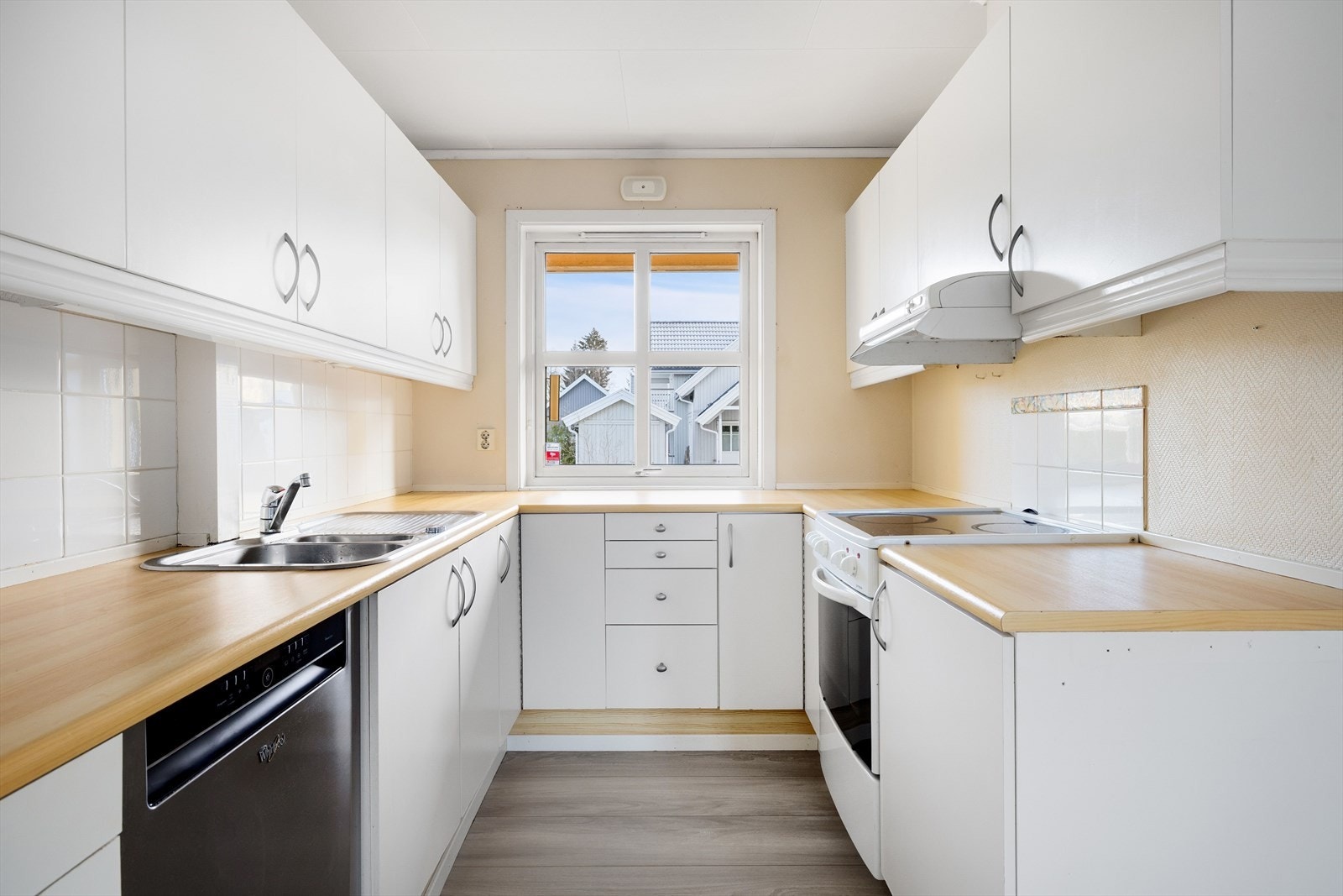 Lys kjøkkeninnredning med god skap- og benkeplass. Innredningen har glatte lysmalte fronter og laminert benkeplate med nedfelt oppvaskkum. Praktisk med lyse fliser i benkeryggen på det ene siden, samt over komfyren. Galleribilde