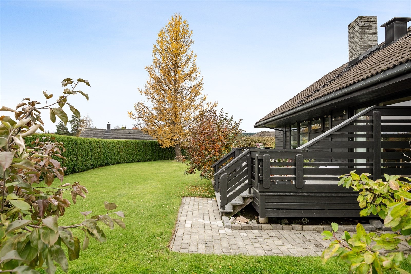 Tomten er meget pent opparbeidet med belegningsstein, plen, hekk og beplanting. Galleribilde