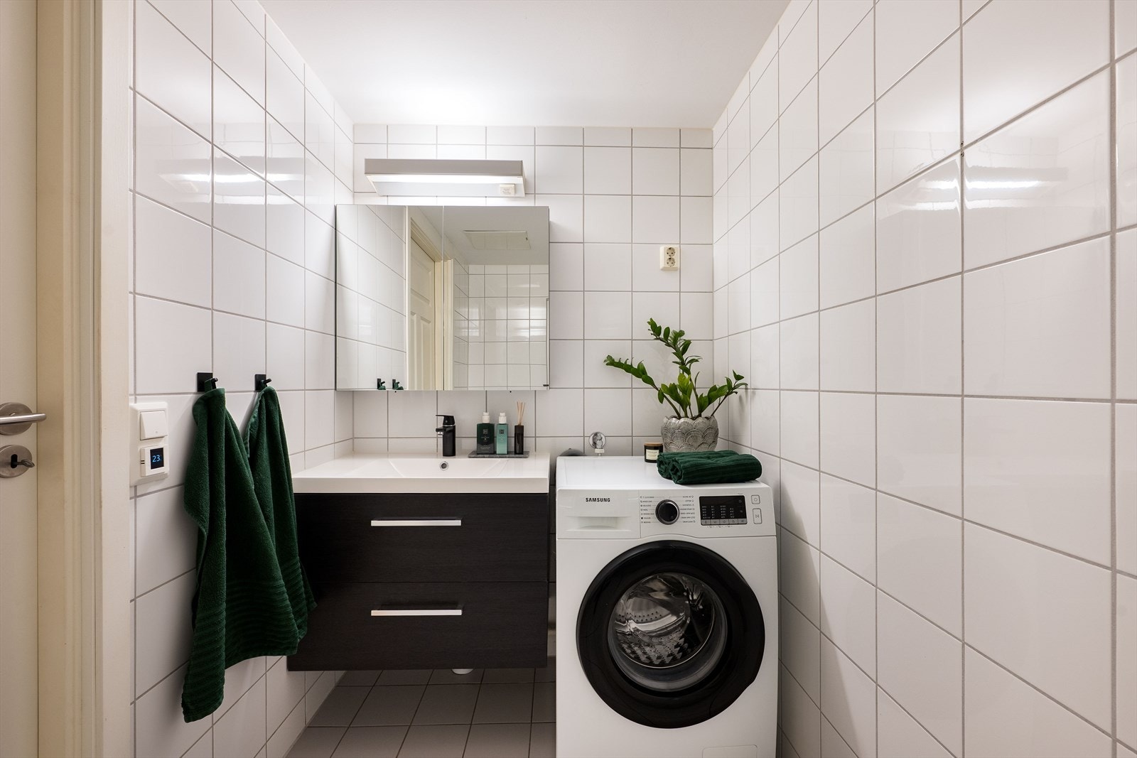 Flislagt bad med dusjhjørne, elektriske varmekabler og opplegg for vaskemaskin. Galleribilde