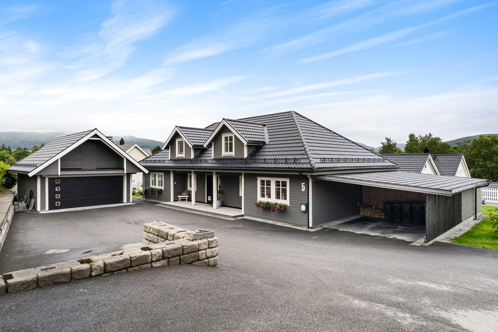 Ute er det flott opparbeidet med asfalt, plen og steinmur. Galleribilde