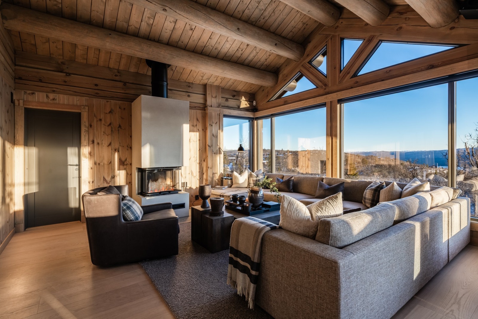Romslig stue med peis og store vindusflater som slipper naturen helt inn - et eksklusivt fristed Galleribilde