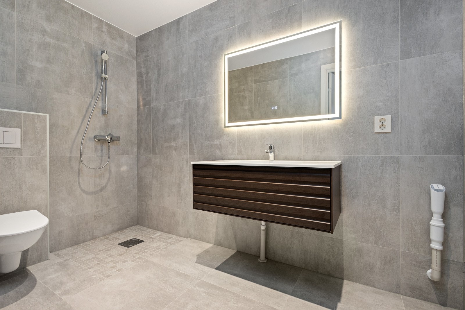 Delikat, flislagt baderom innredet med dusj, servant med skuffeseksjon og klosett. Galleribilde