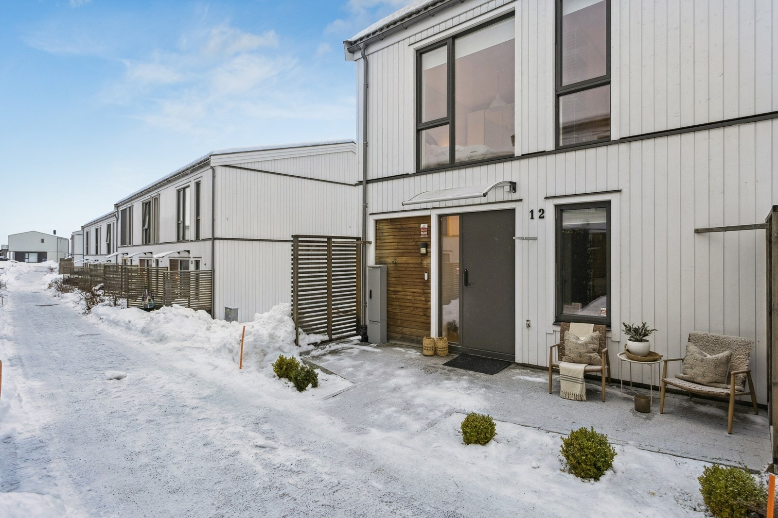 Innbydende inngangsparti pent opparbeidet med grønt beplantning og entrétak med lys. Galleribilde