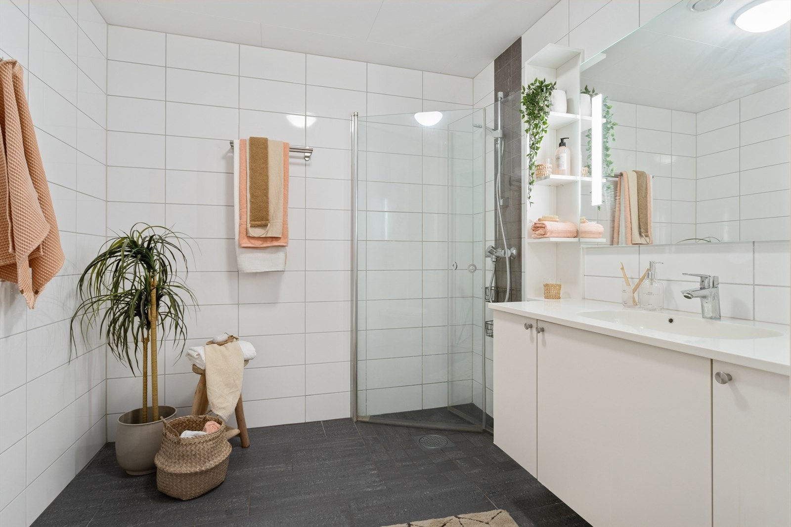 Flislagt bad på 5 m² utstyrt med blant annet gulvvarme, vegghengt klosett, innfellbare dusjvegger og servant med oppbevaringsplass. Galleribilde