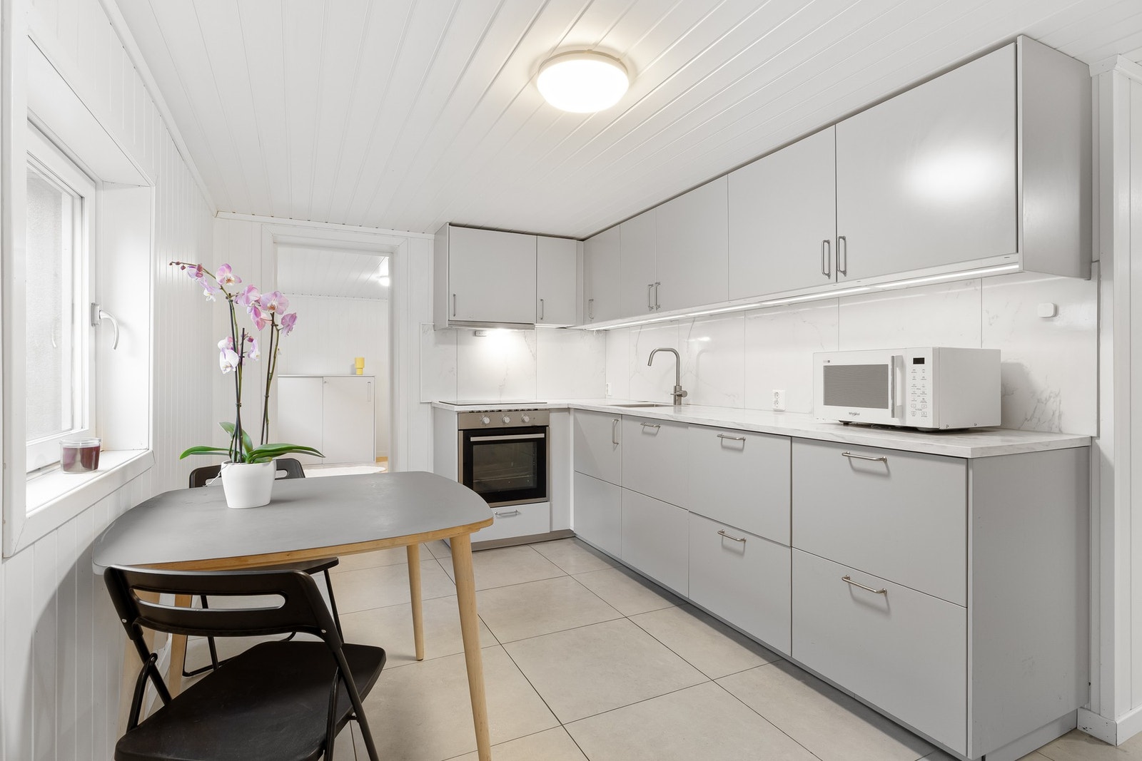 Kjøkkeninnredningen har grå, slette fronter og laminerte benkeplater med nedfelt oppvaskkum. Galleribilde