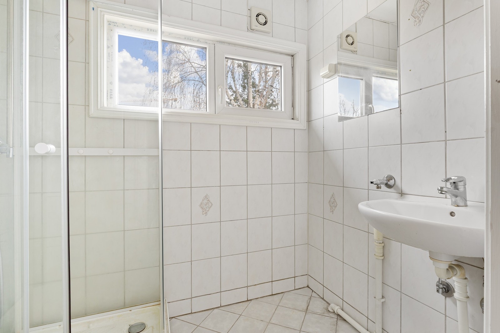 Badet i første etasje har flislagte vegger og gulv. Badet er innredet med servant, toalett, dusjkabinett og opplegg for vaskemaskin. Galleribilde