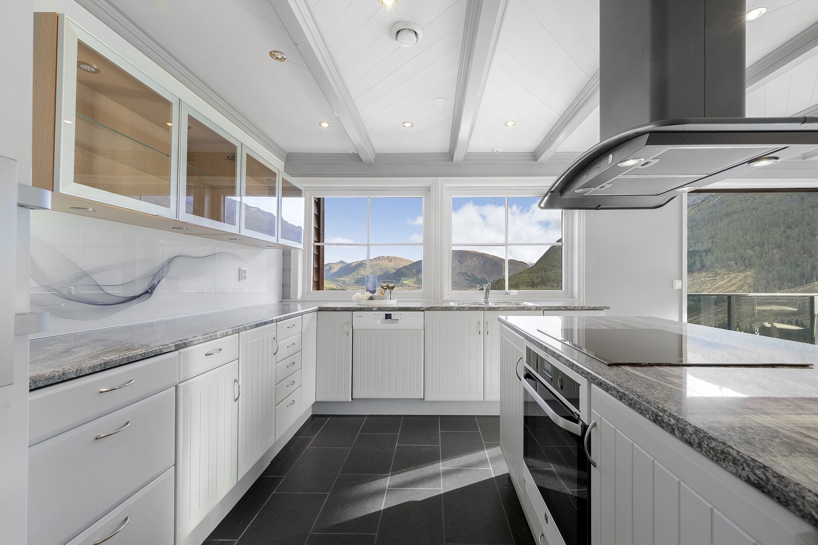 Kjøkkenet har innredning med malte fronter av finér og benkeplate i stein. Galleribilde