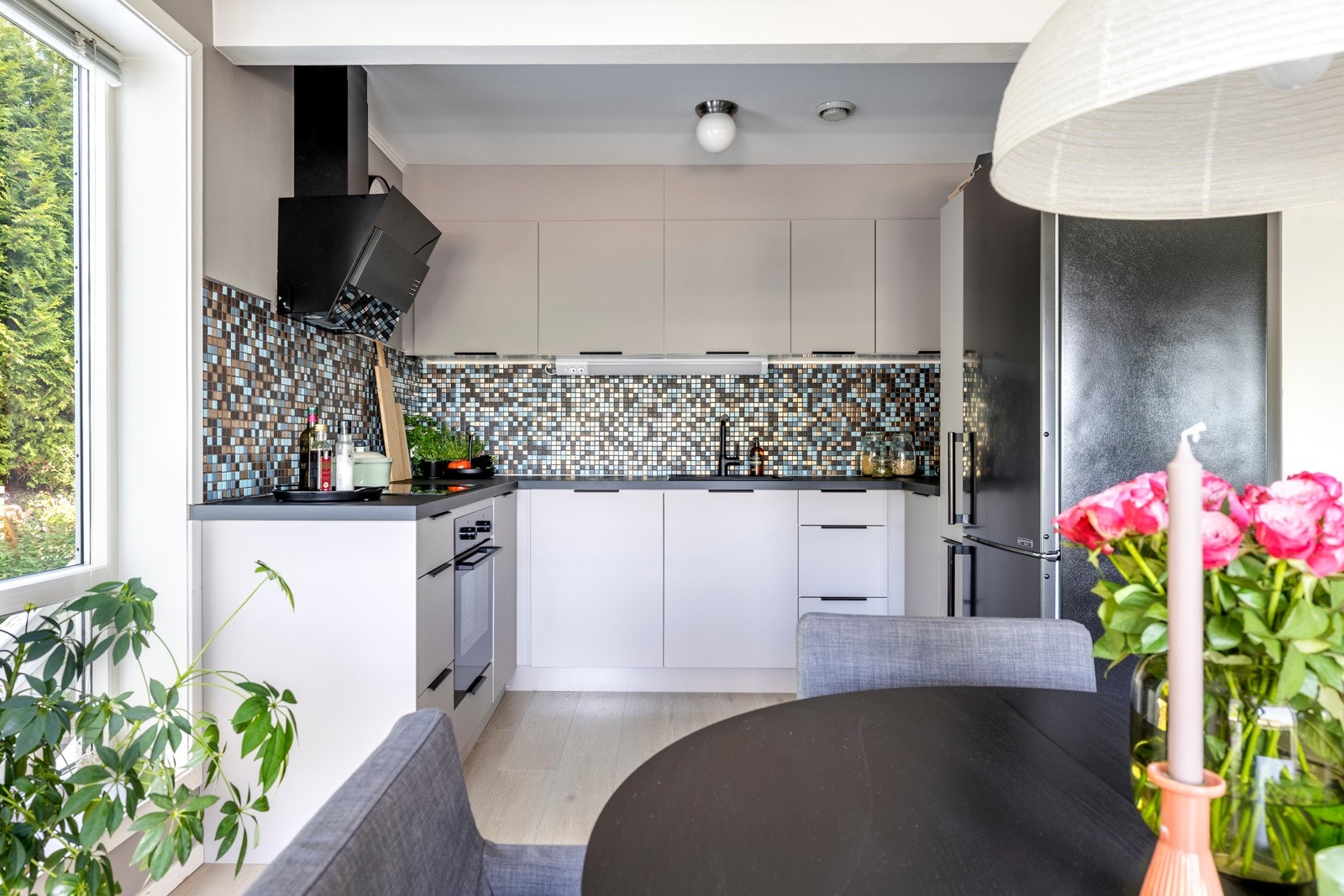 Stilrent og moderne kjøkken med glatte fronter og laminerte benkeplater med nedfelt sort kum og koketopp. Galleribilde