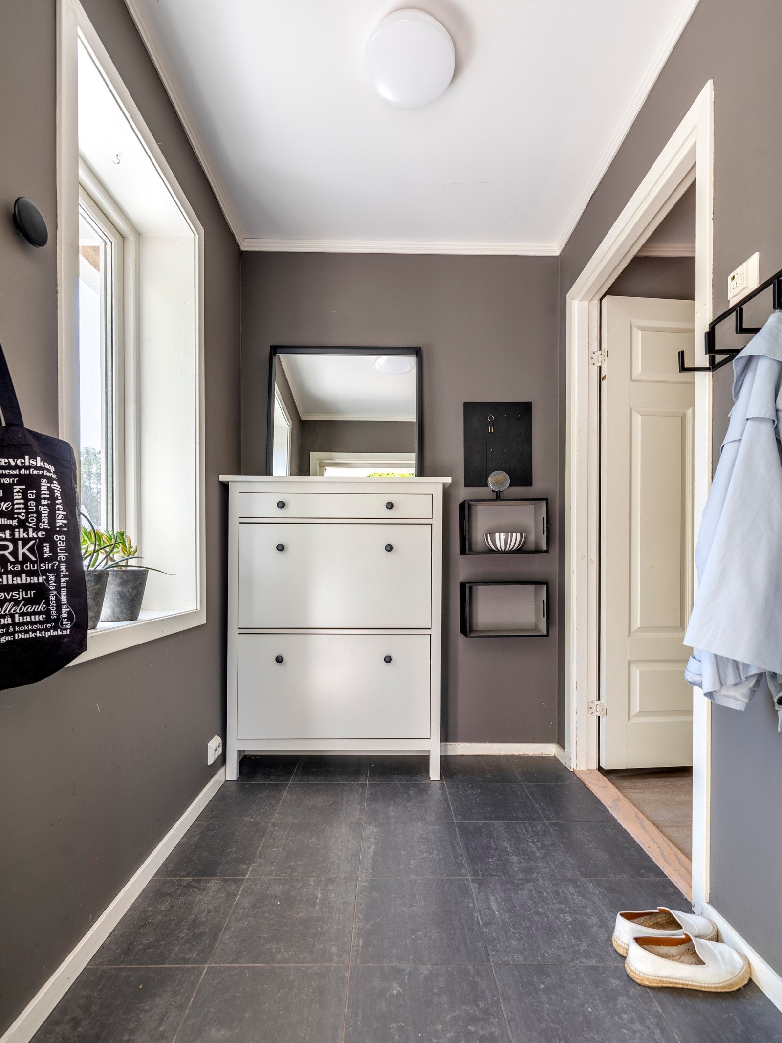 Entréen gir et godt førsteinntrykk av boligen med malte vegger i moderne fargetoner, kombinert med grå gulvfliser som er utstyrt med behagelig gulvvarme. Galleribilde