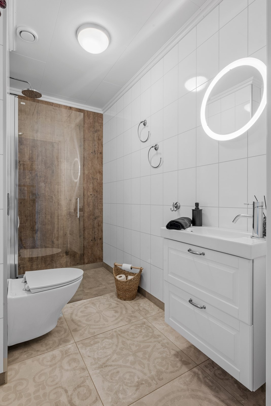 De flotte flisene fortsetter inn til badet. Badet er utstyrt med vegghengt toalett, regndusj og stilren servant. Galleribilde