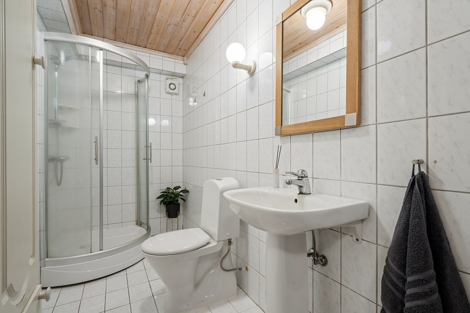 Badet i underetasjen er helfliset med lyse, sjatterte fliser på gulv og vegger. I gulvet har man også varmekabler for ekstra komfort. Badet er ellers innredet med dusjkabinett, toalett og servant. Galleribilde