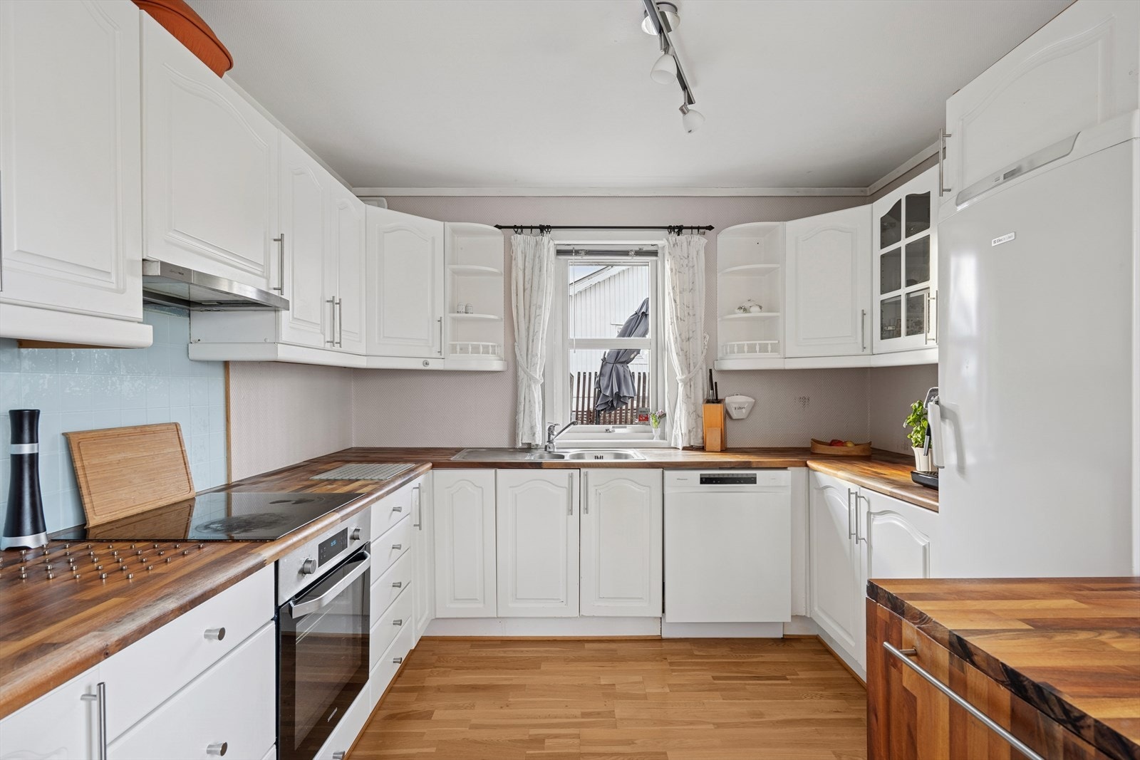 Kjøkkenet er innredet med hvite, profilerte fronter og trefarget benkeplate av heltre. Her har man rikelig med skap- og skuffeplass, samt gode arbeidsflater på benk. Galleribilde