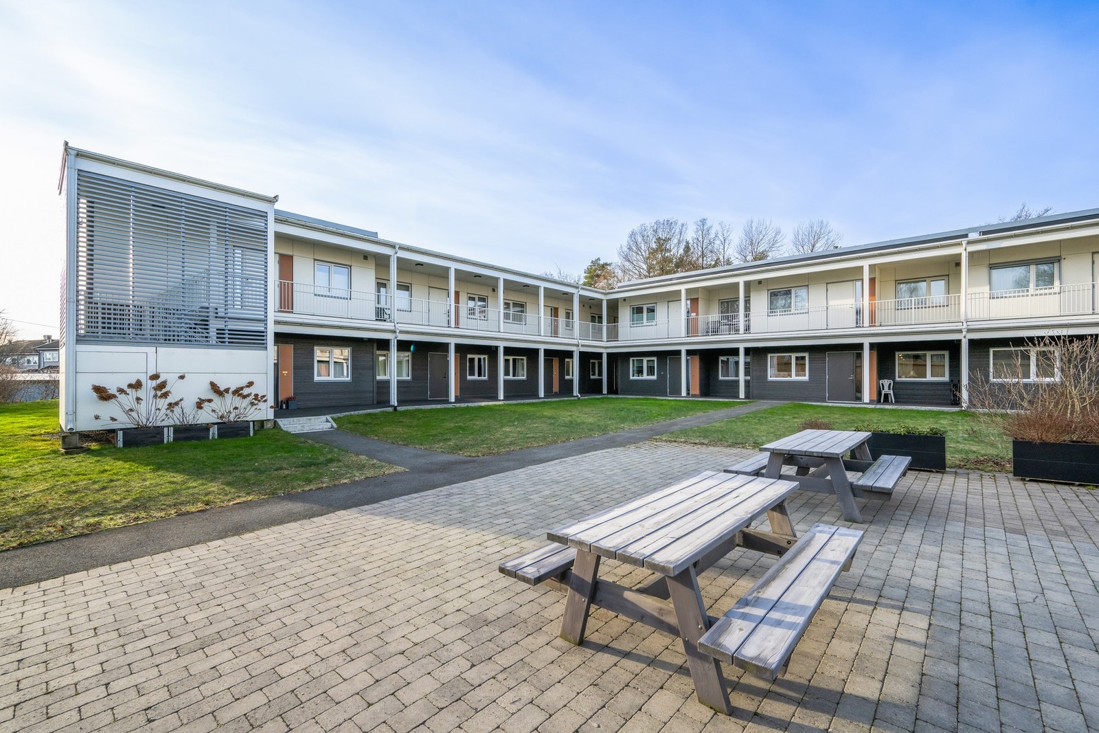 Hyggelig atrium og fellesareal mot svalegang og inngangsparti. Dør 3 fra venstre er til leiligheten. Galleribilde