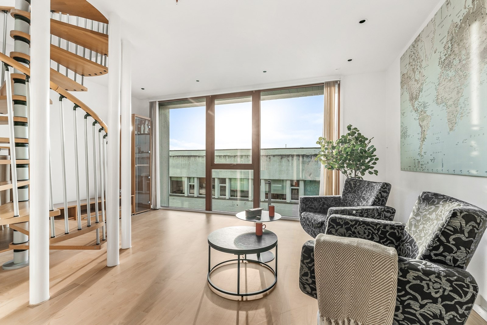 Store vindusflater som slipper godt med dagslys inn leiligheten. Kontorbygg på motsatt side av veien. Galleribilde