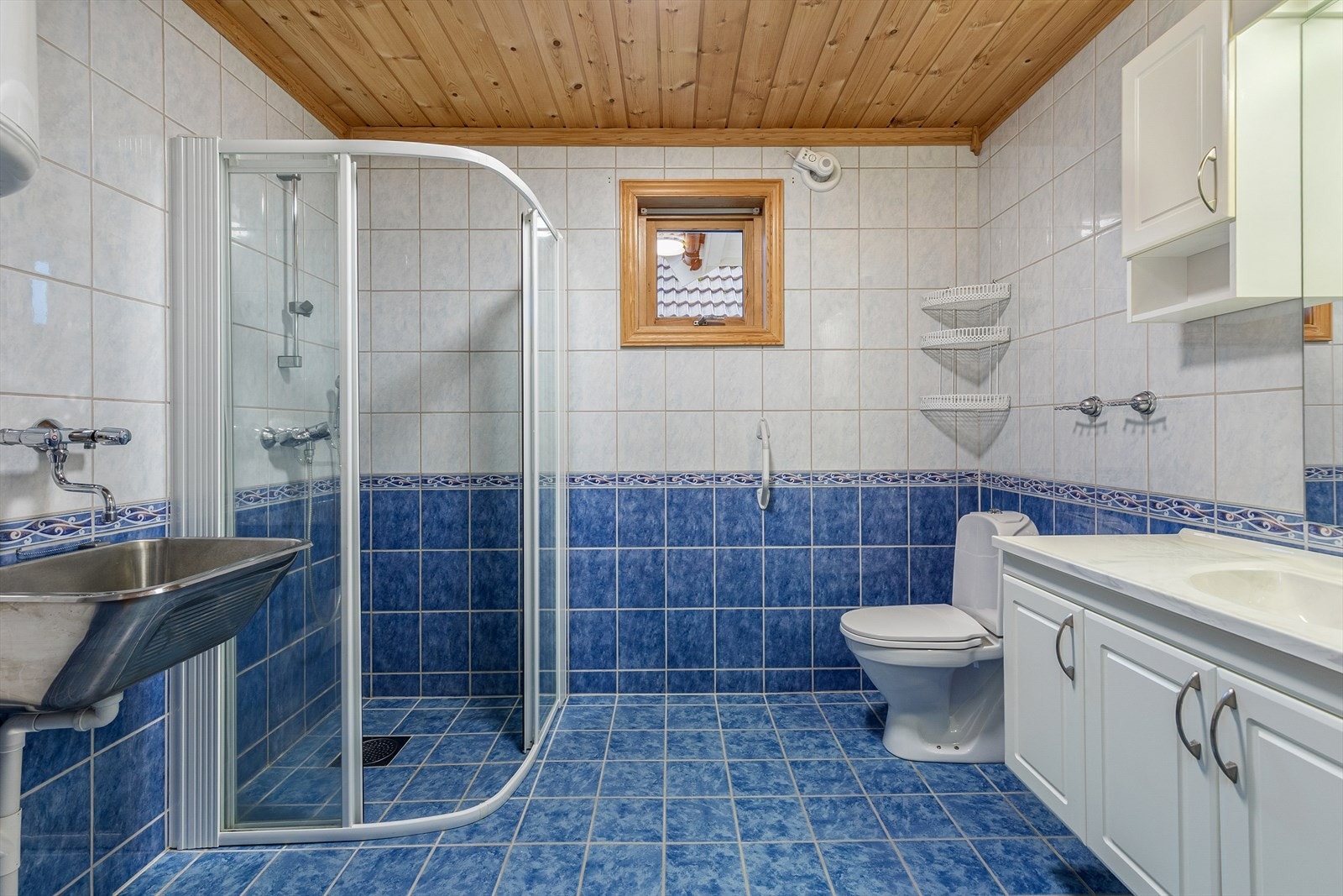 Heilflisa bad utstyrt med toalett, dusjhjørne, utslagsvask og innredning med servant. Galleribilde