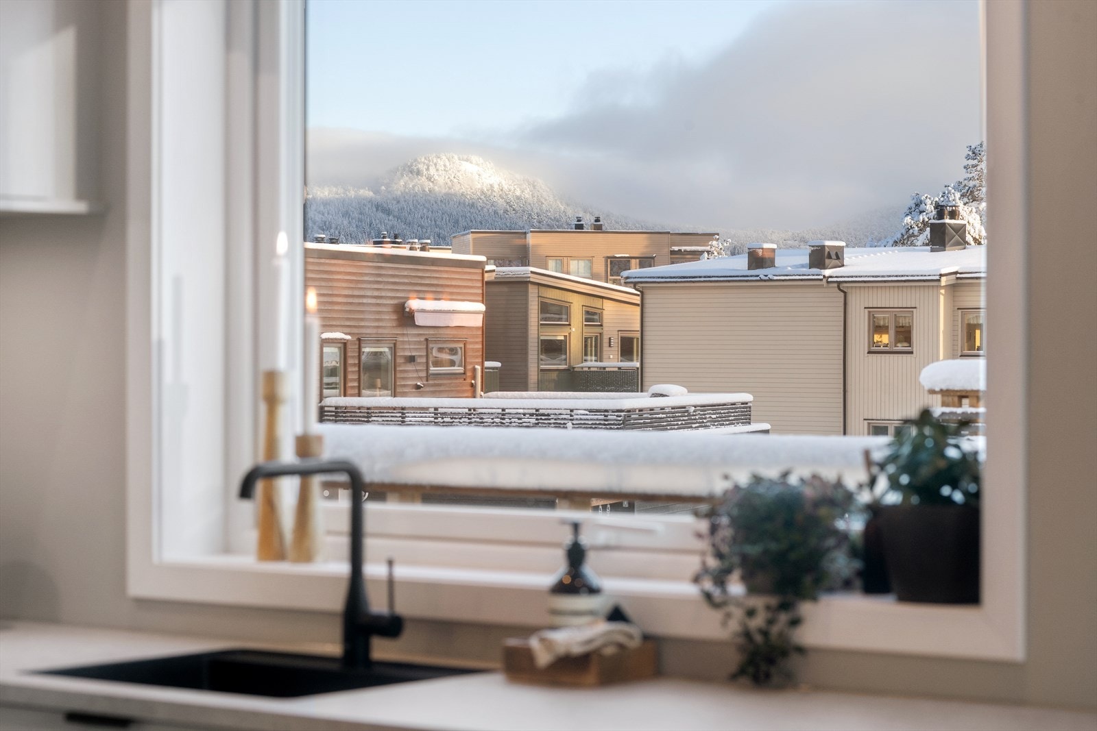 Utsikt fra kjøkkenvasken mot nabolaget og fjellene i bakkant. Galleribilde