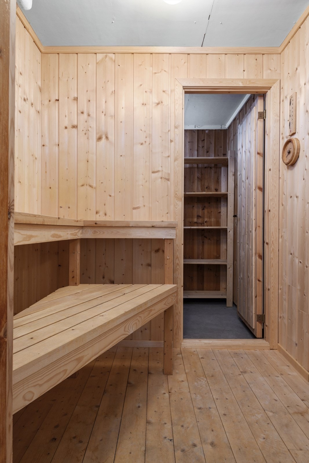 Videre adkomst til badstue med tregulv, overflater med panel og vedfyrt badstueovn. Galleribilde