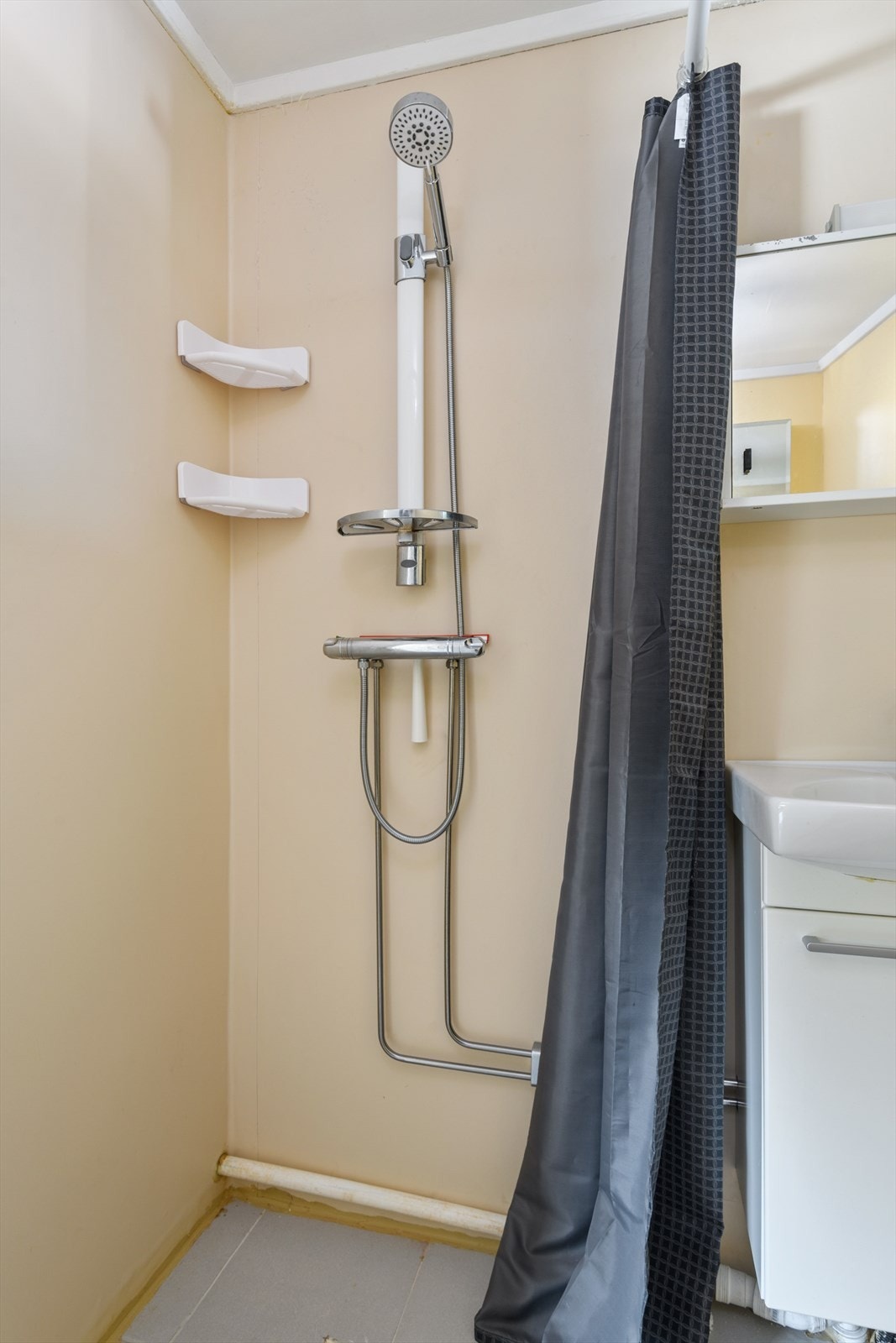 Rommet er utstyrt med servantskap, speilskap, dusjhjørne med forheng og gulvmontert toalett. Galleribilde