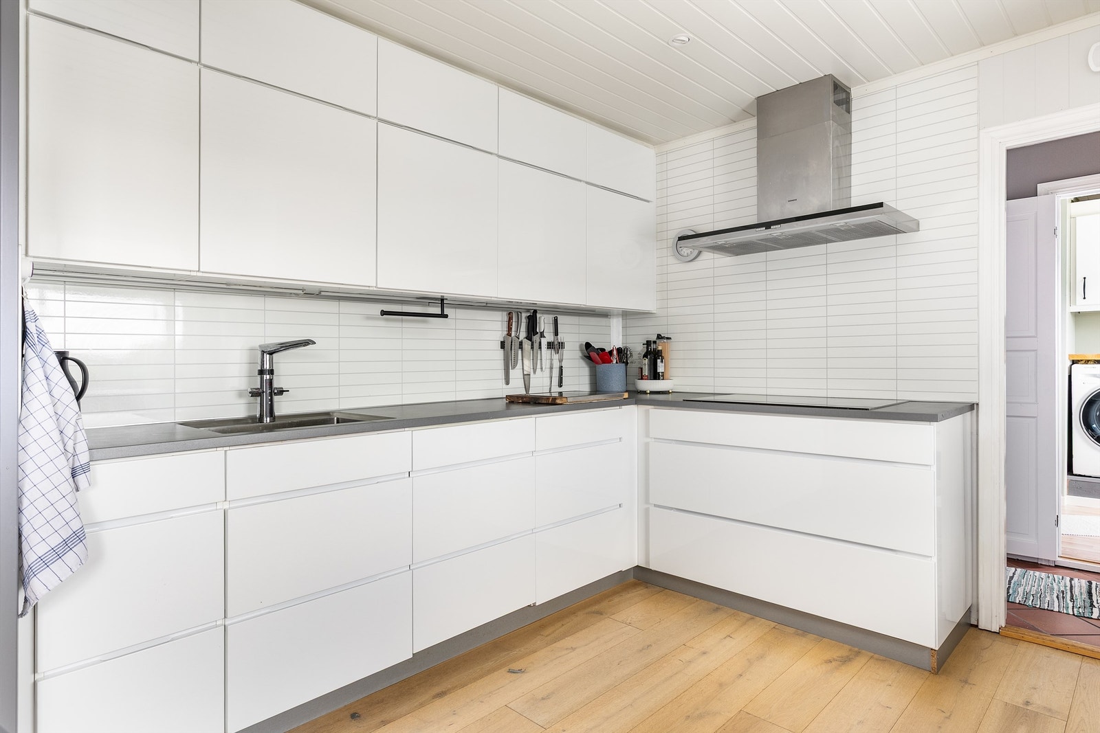 Platetoppen har induksjon og er av ekstra bred modell. Vasken er underlimt benkeplaten og utstyrt med berøringsfritt armatur. Galleribilde