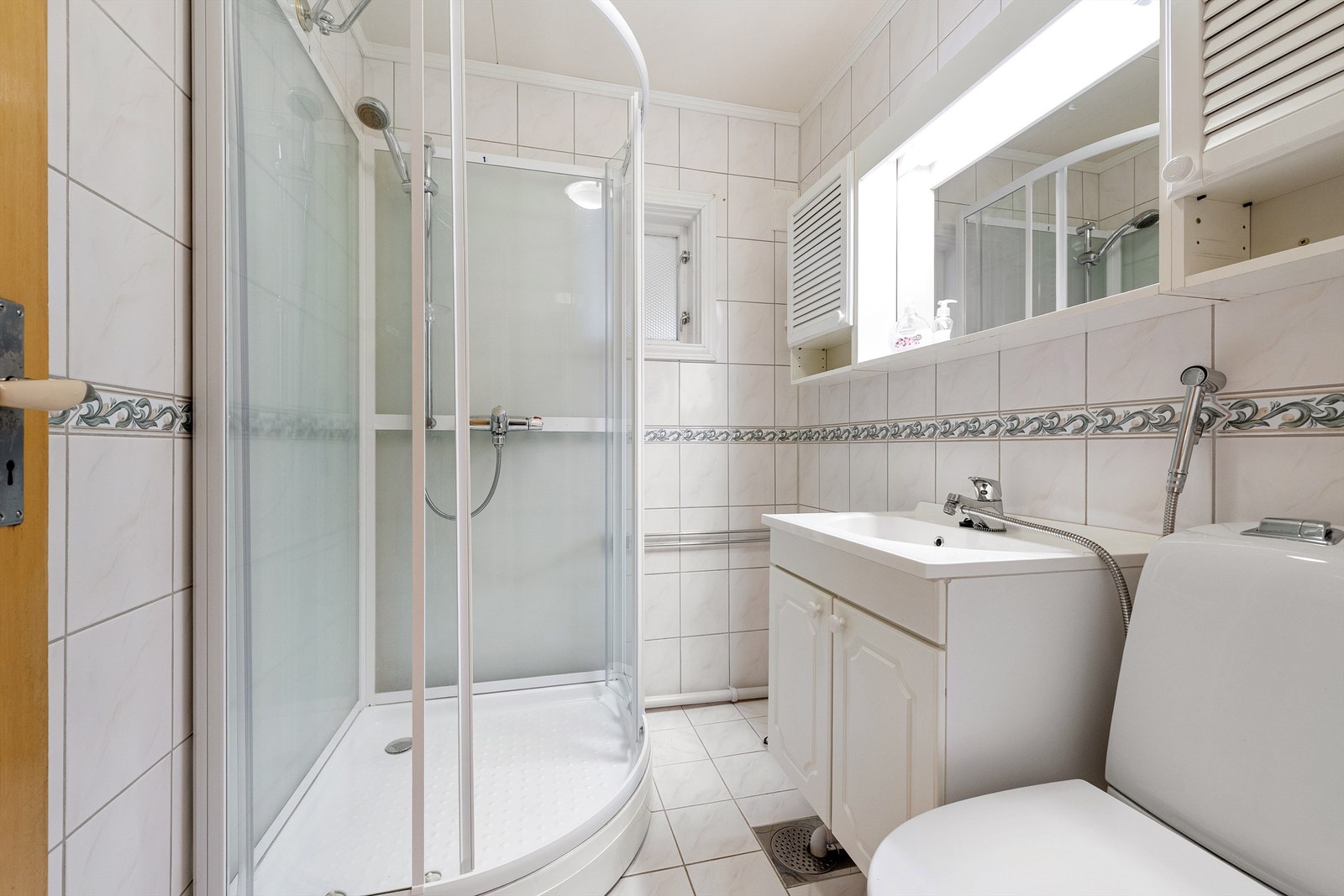 Flislagt bad med innredning, toalett og dusjkabinett Galleribilde