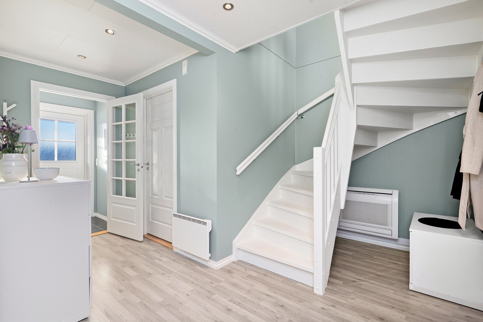 Trappegang i 1.etasje. Også 1.etasje er lys og malt i fine farger. Under trappen står varmepumpe nr.2 Galleribilde