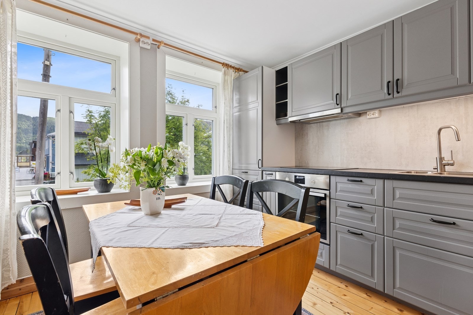 Kjøkkenet fremstår lyst, moderne og funksjonelt, med god skap- og benkeplass. Store vindusflater slipper inn rikelig med dagslys og gir god utsikt mot nærområdet, samtidig som de skaper en luftig og trivelig atmosfære. Galleribilde