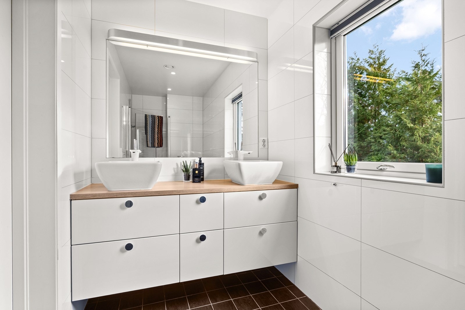 Pent flislagt bad med mye varmekabler i gulv, dobbelservant og mye oppbevaringsplass Galleribilde