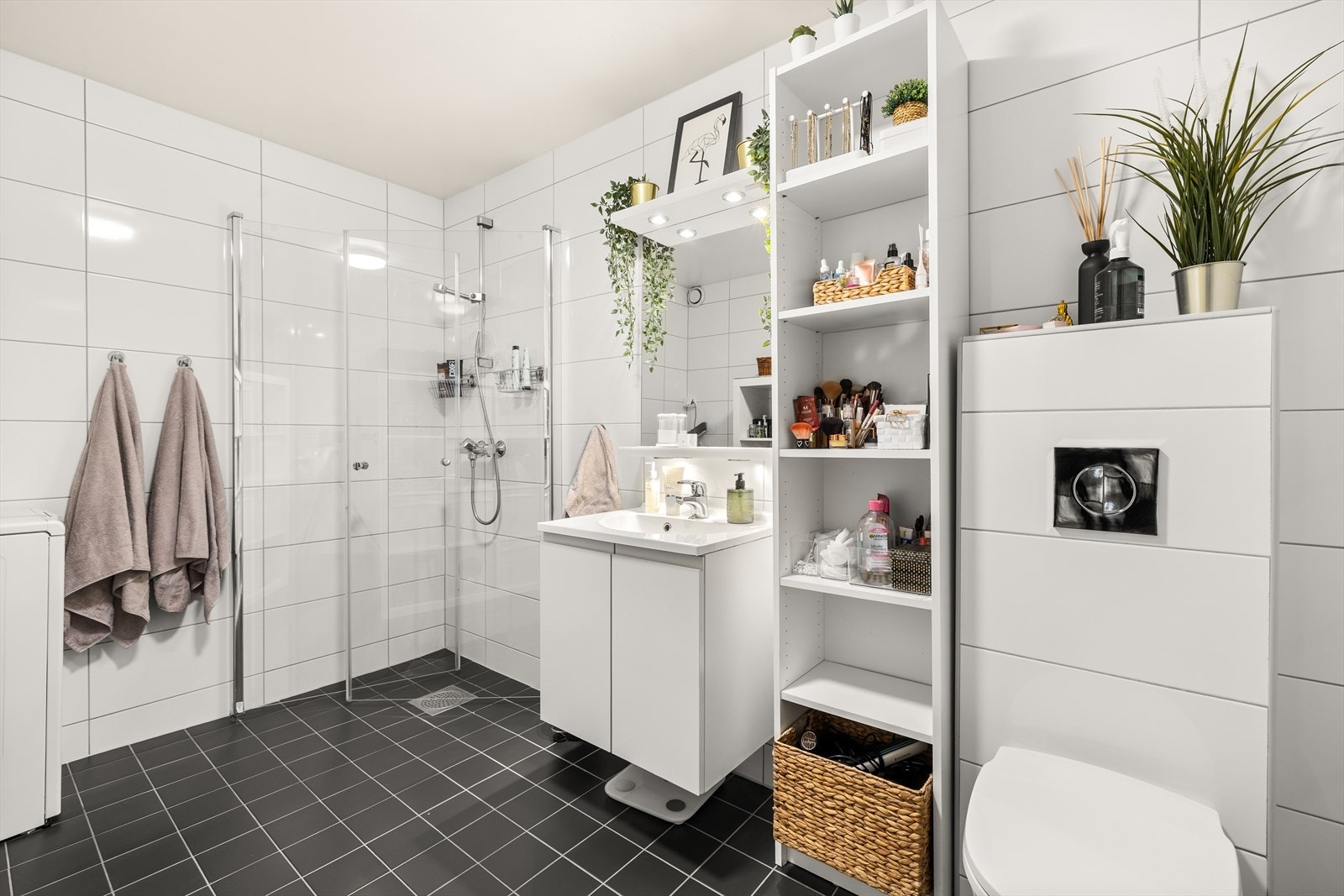 Pent flislagt bad i kjeller med varmekabler i gulv, dusjhjørne, toalett, opplegg for vaskemaskin og servant med innredning Galleribilde