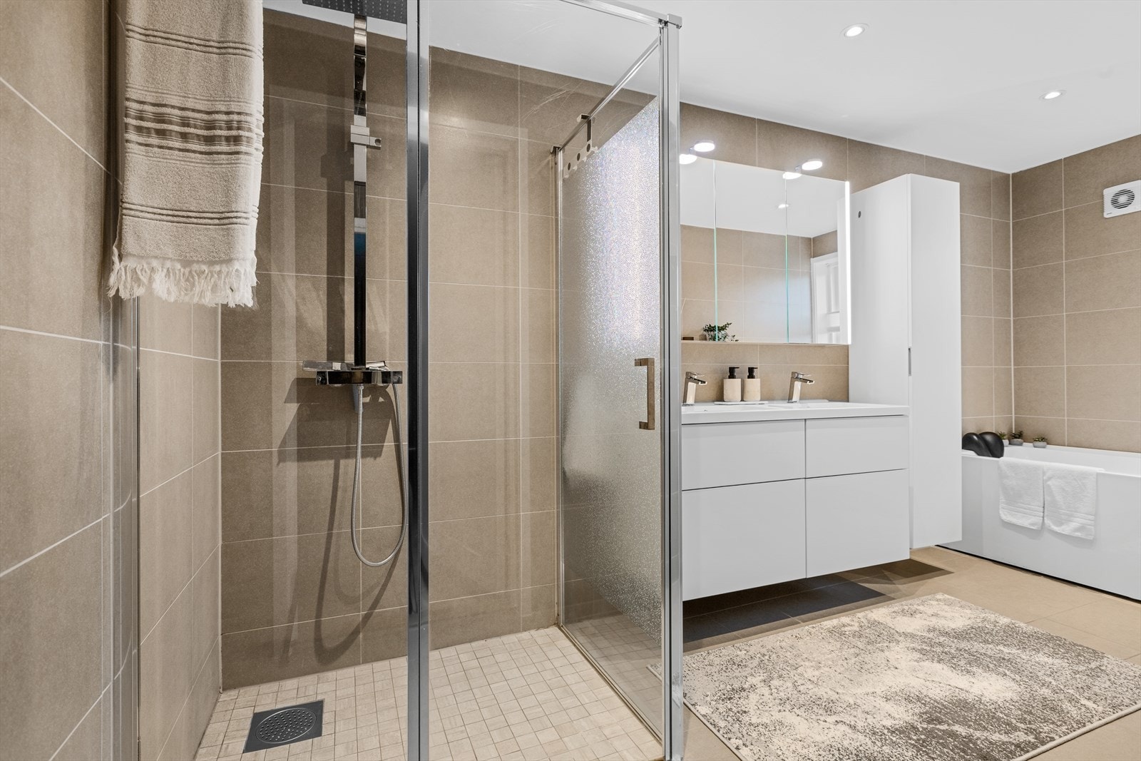 Baderommet er lekkert innredet med lys innredning, dobbel heldekkende servant, speilskap med belysning og rikelig oppbevaringsplass i under- og overskap. Galleribilde