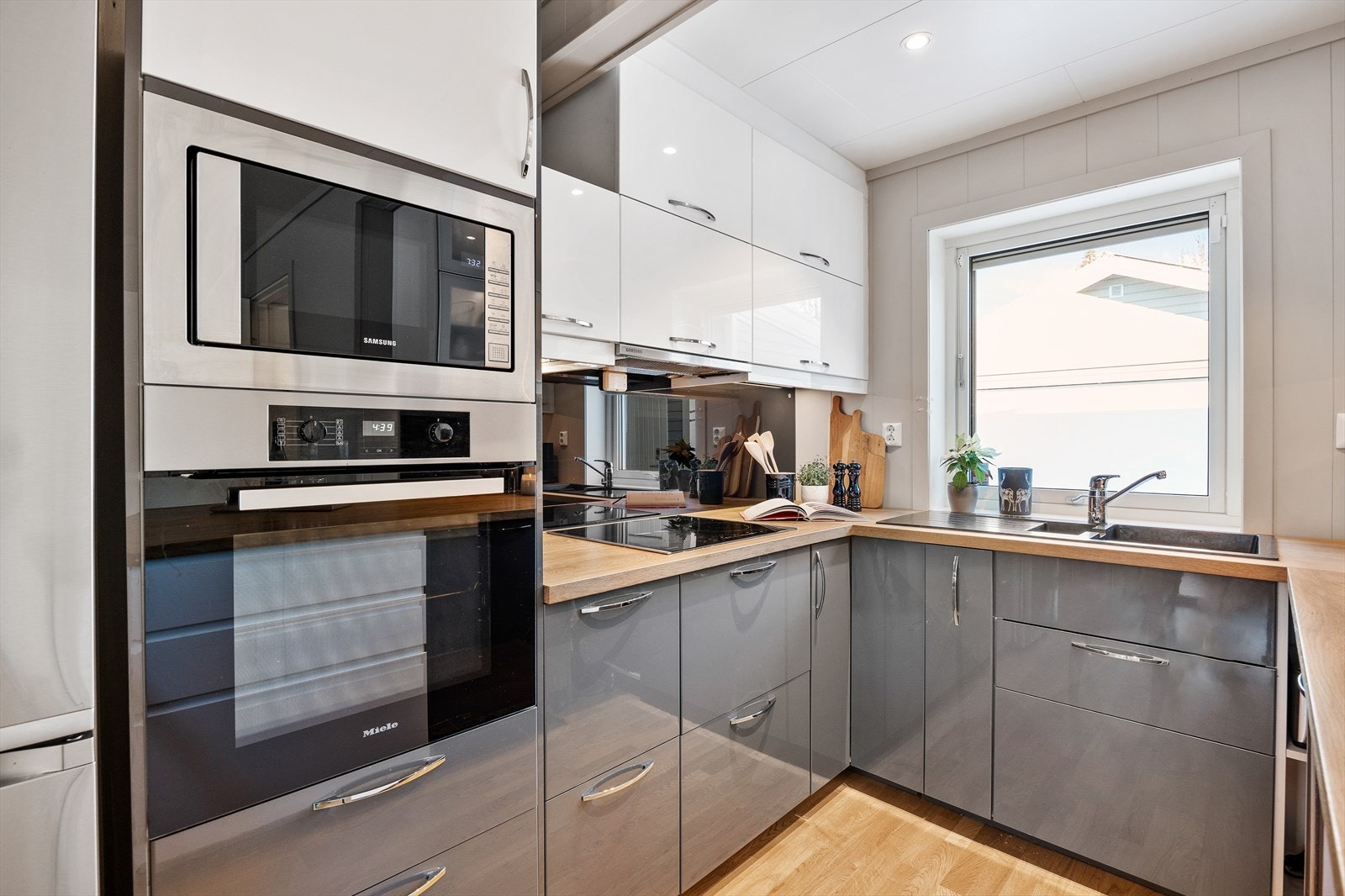 Innredningen består av mørke/hvite/glatte fronter, benkeplate med laminatbelegg, glassplater mellom benkeplate og overskap og sort vask. Galleribilde