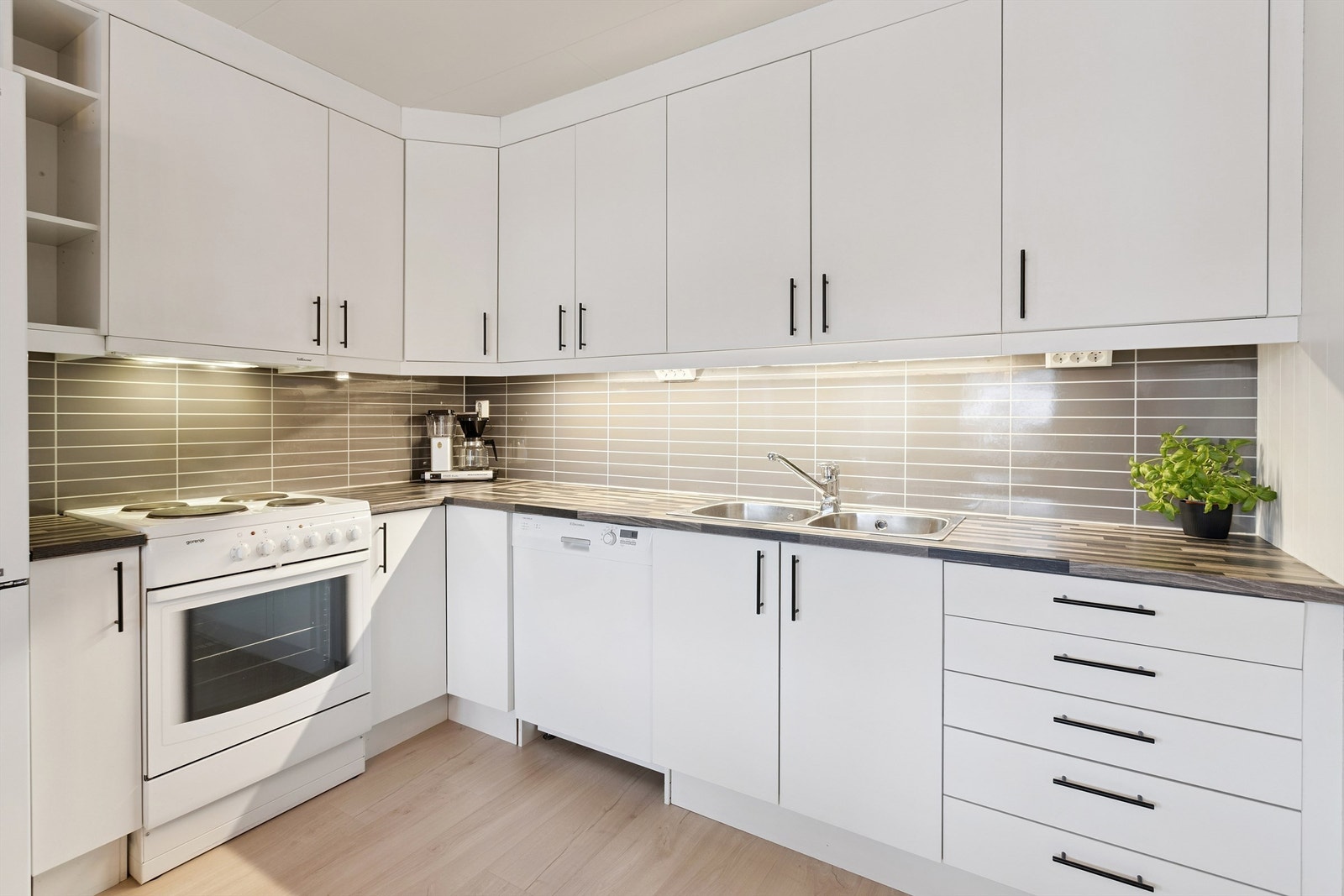 Kjøkkeninnredning med malte fronter, laminatbenkeplate og opplegg for oppvaskmaskin. Galleribilde