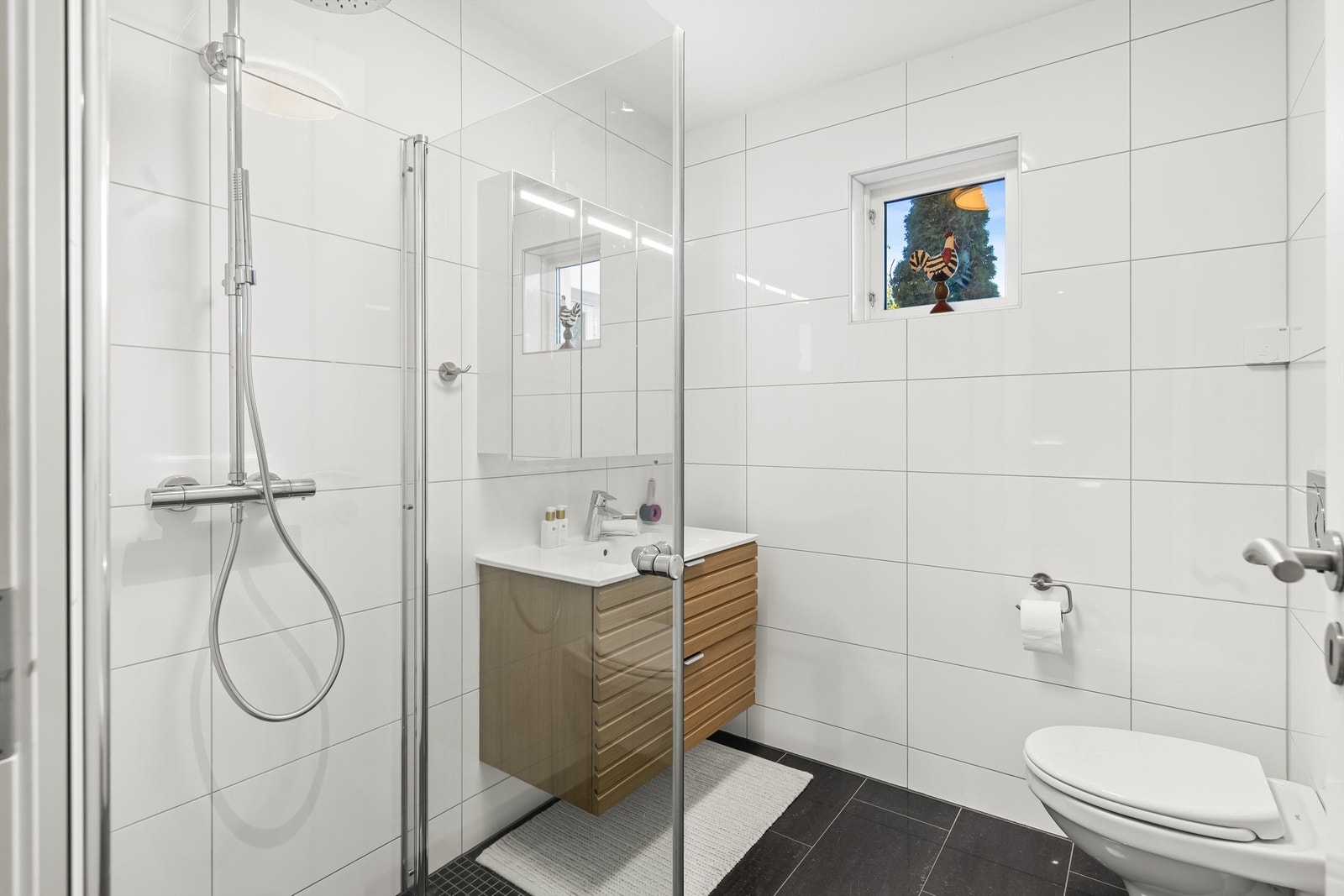 Badet i 1. etasje er pent innredet med flis på gulv og vegger. Det er vannbåren varme i gulvet. Selve baderomsinnredningen ble oppgradert i 2023. Galleribilde