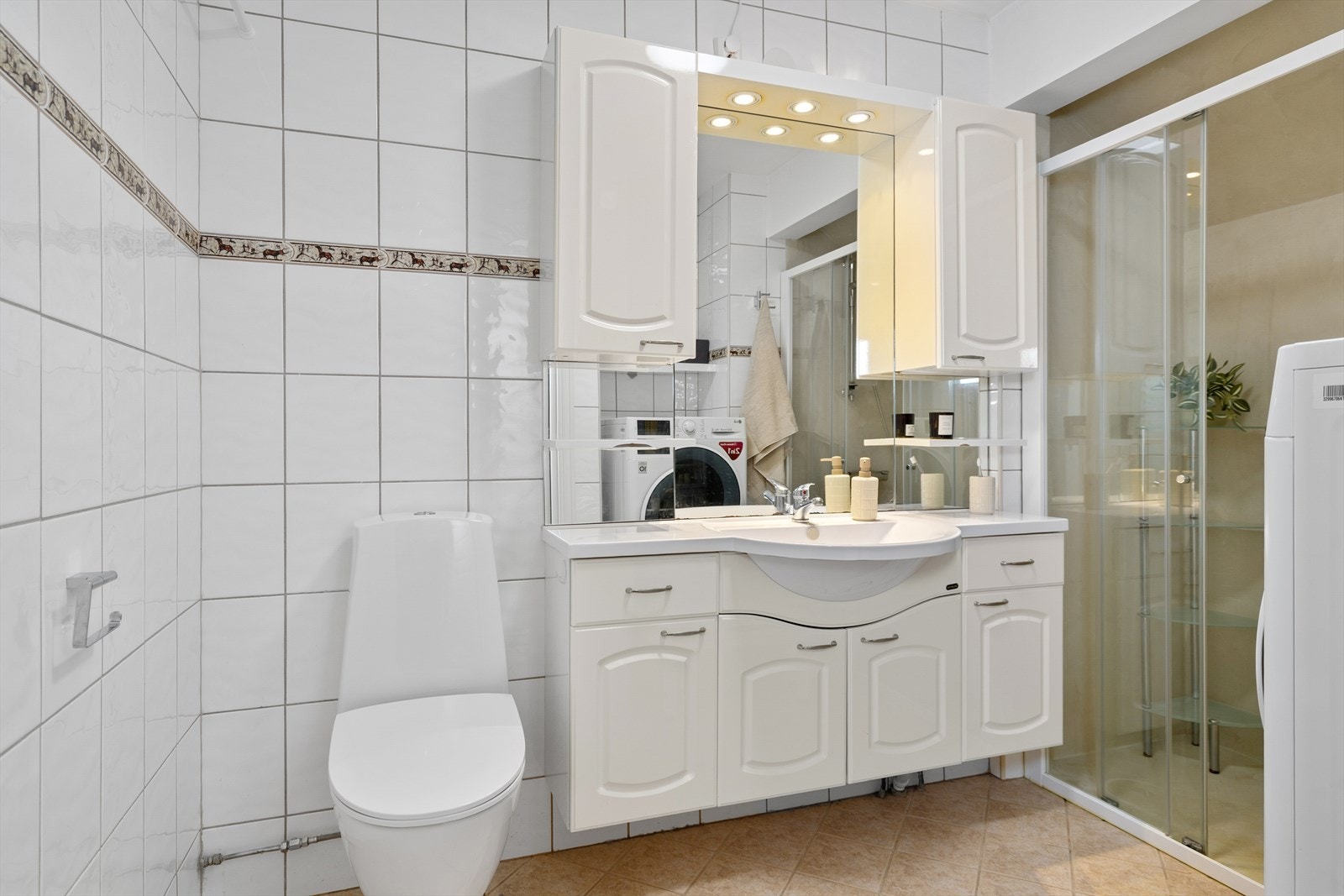 Badet er flislagt med varme i gulvet. Innredet med servant, dusjhjørne, toalett og opplegg for vaskemaskin. Galleribilde