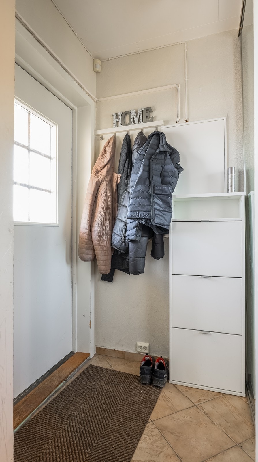 Velkommen til Hoveddel - Romslig entré med fliser på gulv og skyvedørsgarderobe Galleribilde