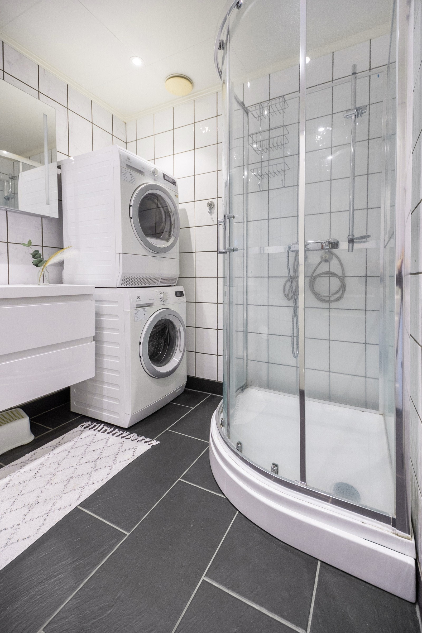 Badet inneholder servant med skuffer, speilskap med belysning, toalett og dusjkabinett. Galleribilde