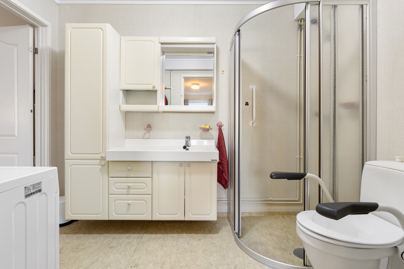 Baderom fra byggeår med dusjhjørne, servantinnredning og opplegg for vaskemaskin. Badet har elektrisk gulvvarme og mekanisk avtrekk. Galleribilde