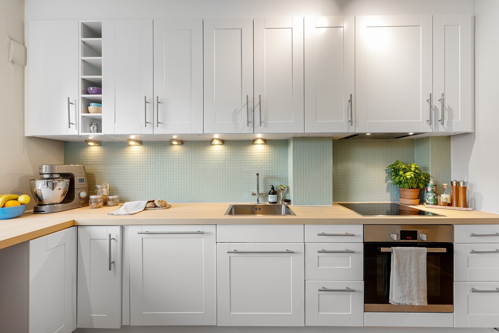 Kjøkkenet har profilerte fronter med god skap og benkeplass. Benkeplaten er av laminat (2023) med en nedfelt vaskekum og belysning over benkeplaten. Videre er det Integrert platetopp, oppvaskmaskin, stekeovn og frittstående kjøle-/fryseskap. Galleribilde