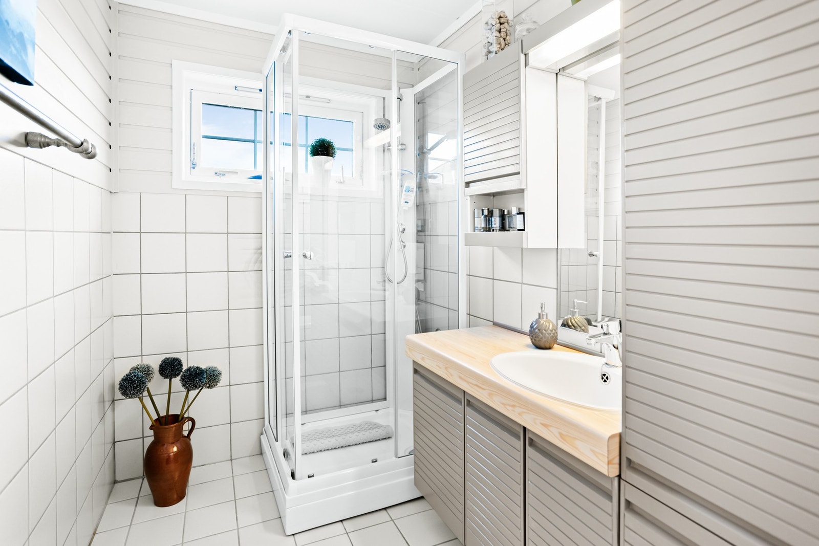 Badet i 1. etasje har gulv med flis, vegger med flis og trepanel, og himling med himlingsplater. Galleribilde