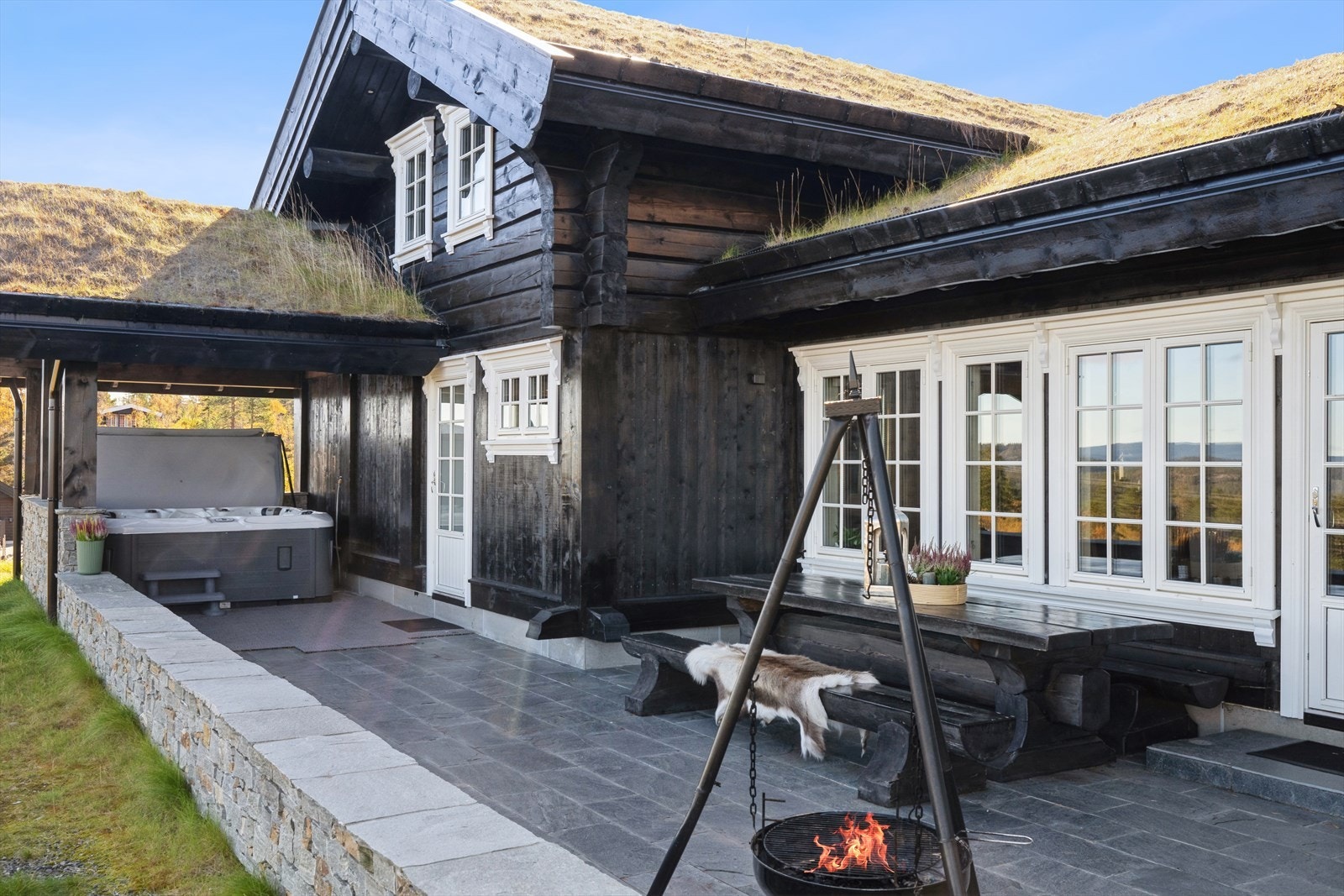 Flott uteområde foran hytta med steinlagt uteplass og jacuzzi under tak Galleribilde