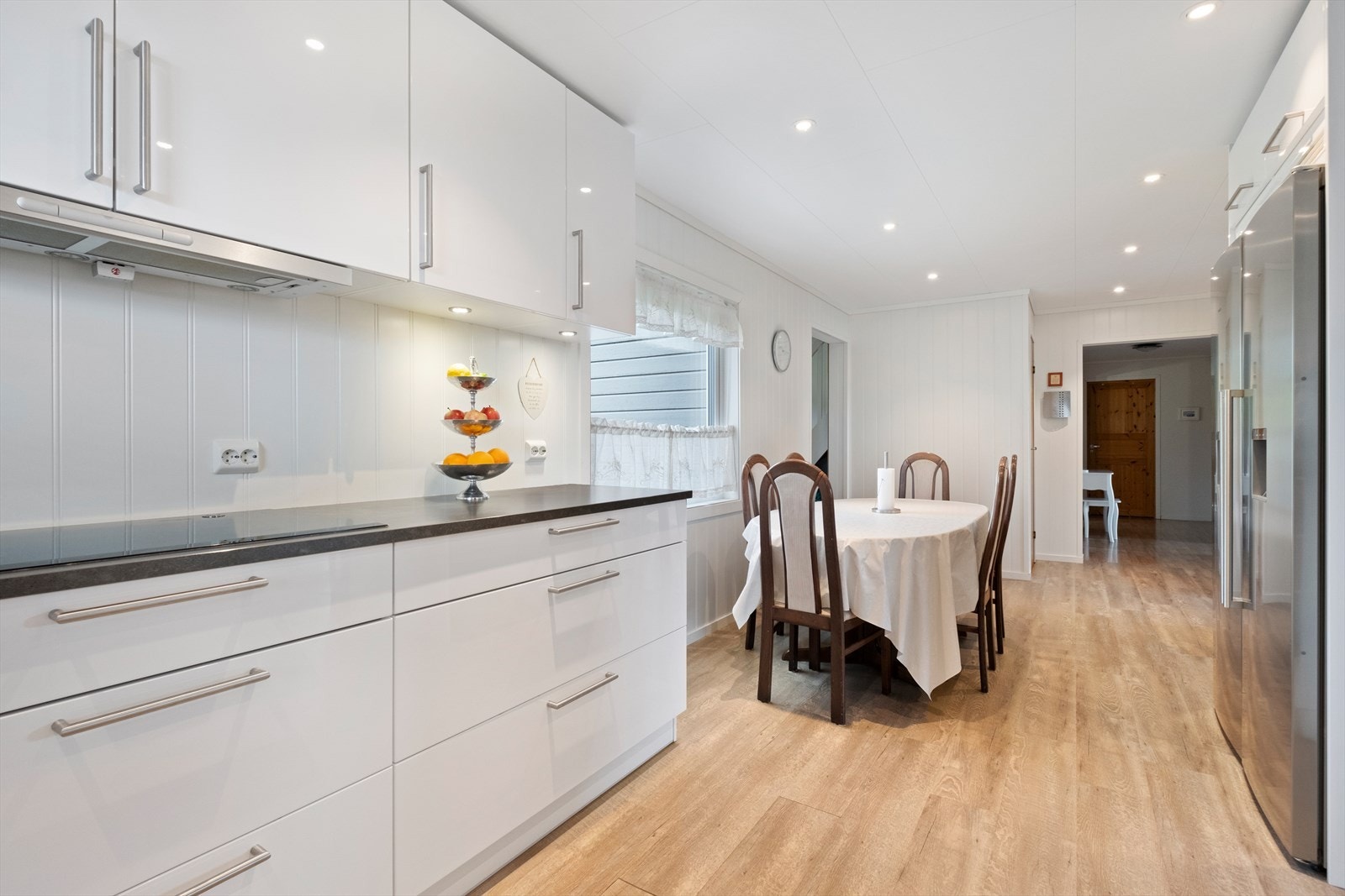 Det er ventilator over integrert koketopp med avtrekk ut. Det er integrert stekeovn, mikrobølgeovn og oppvaskmaskin. Opplegg for kjøleskap med vanndispenser. Laminat
benkeplate med nedfelt oppvaskkum Galleribilde