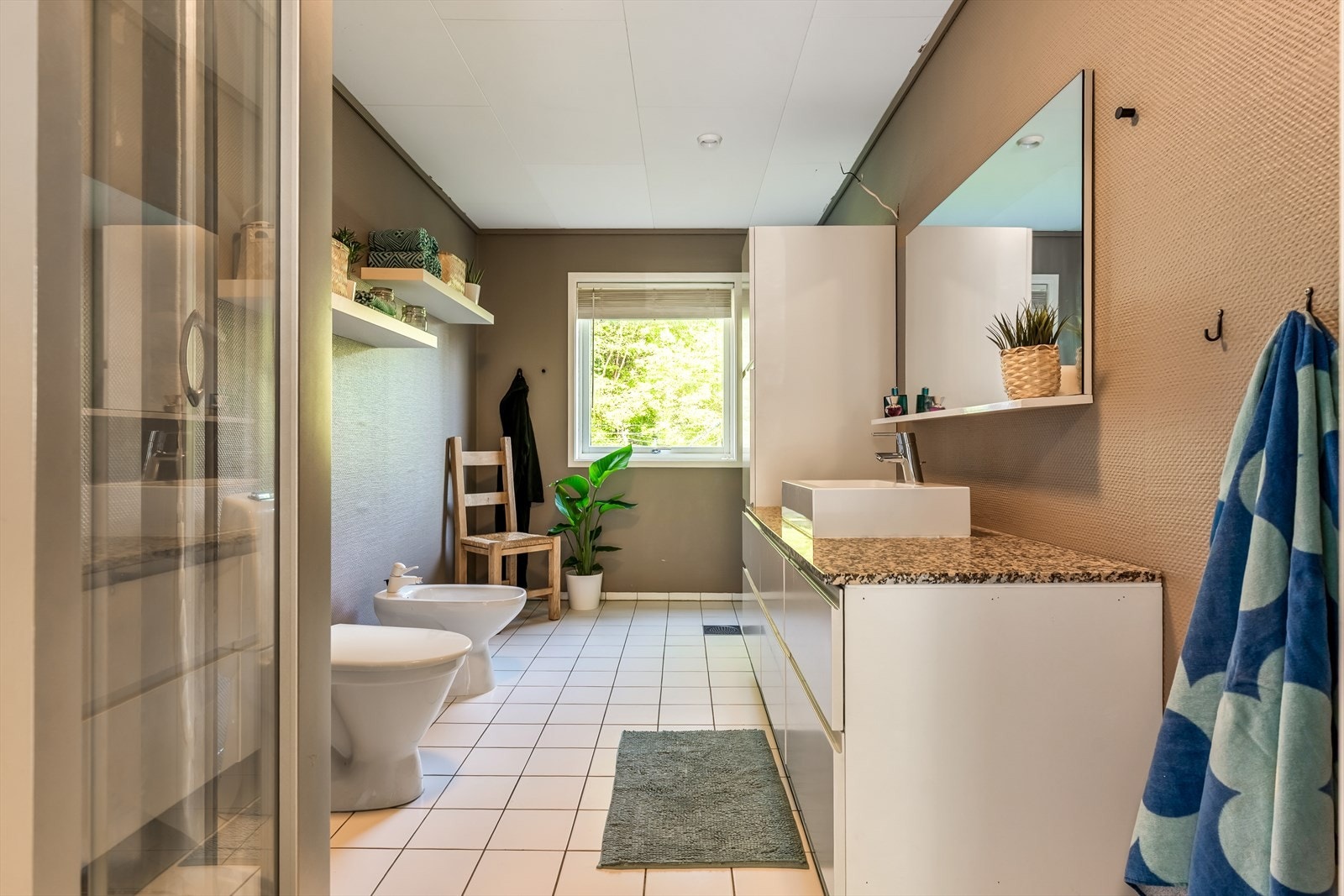 Stort baderom på ca. 9,5 kvm innredet med servant, servantskap og utstyrt med toalett, dusjhjørne og en lav vaskeservant. Galleribilde