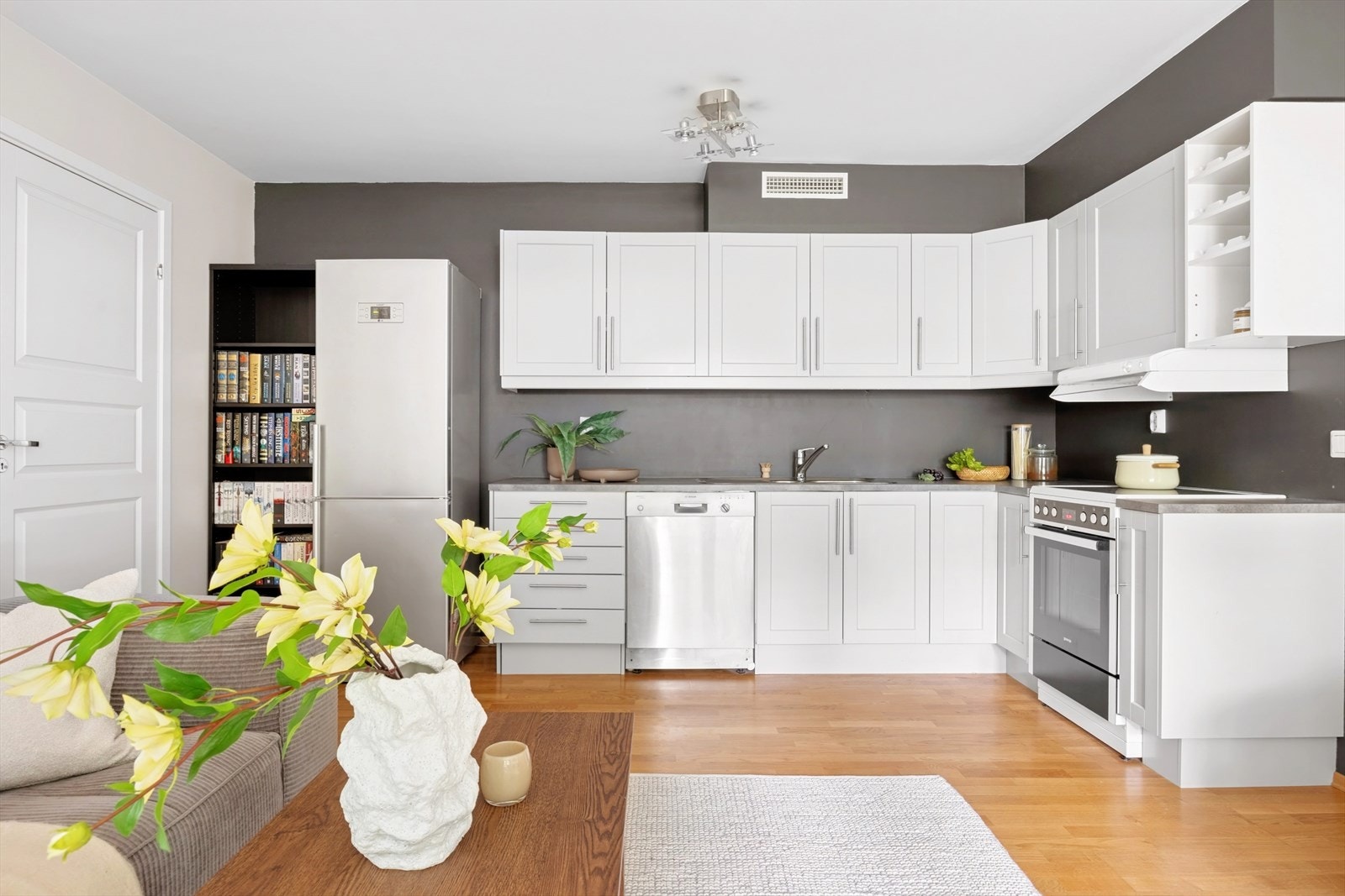 Stilrent kjøkken, innredning av profilerte, hvite fronter og benkeplate av laminat med nedfelt vask av stål. Galleribilde